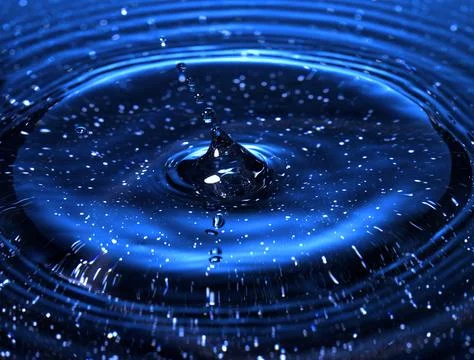 Splash - a drop falling onto the water surface in a color macro shot Fotos de archivo