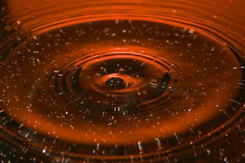 Splash - a drop falling onto the water surface in a color macro shot Stock Photos