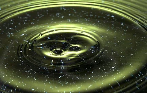 Splash - a drop falling onto the water surface in a color macro shot Stock Photos