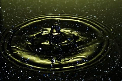 Splash - a drop falling onto the water surface in a color macro shot Stock Photos