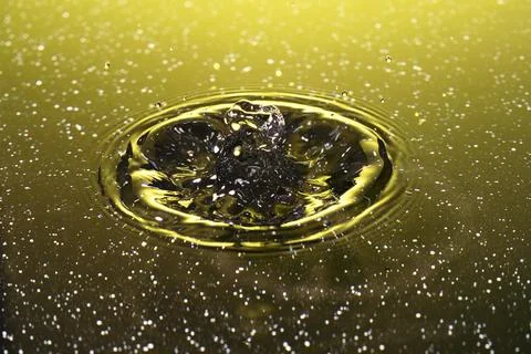 Splash - a drop falling onto the water surface in a color macro shot Stock Photos