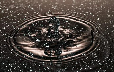 Splash - a drop falling onto the water surface in a color macro shot Stock Photos