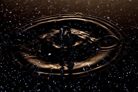 Splash - a drop falling onto the water surface in a color macro shot Stock Photos