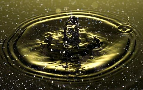 Splash - a drop falling onto the water surface in a color macro shot Stock Photos