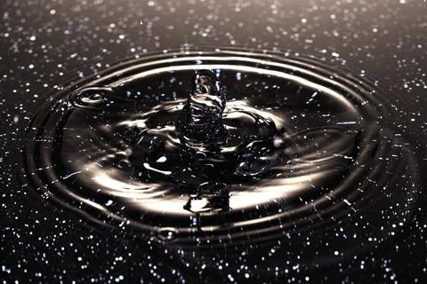 Splash - a drop falling onto the water surface in a color macro shot Stock Photos