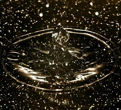 Splash - a drop falling onto the water surface in a color macro shot Stock Photos