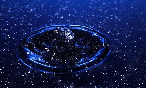 Splash - a drop falling onto the water surface in a color macro shot Stock Photos