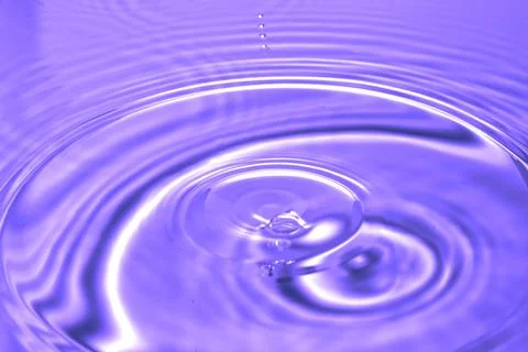 Splash - a drop falling onto the water surface in a color macro shot Stock Photos