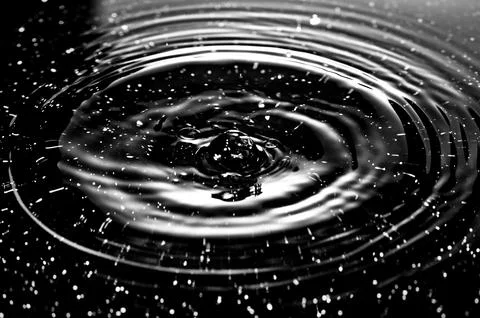 Splash - a falling drop of water breaking on the water surface Stock Photos