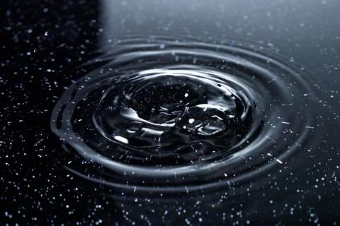 Splash - a falling drop of water breaking on the water surface Stock Photos