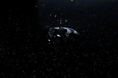 Splash - a falling drop of water breaking on the water surface Stock Photos