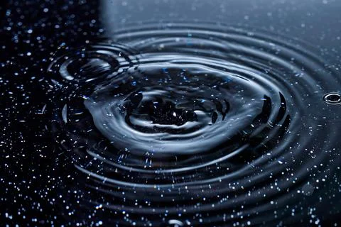 Splash - a falling drop of water breaking on the water surface Stock Photos