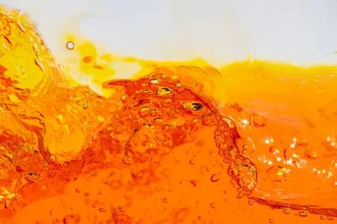 Splash of orange liquid with bubbles and foam on surface Stock Photos