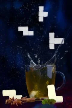 Splash. Plop. Tea and falling sugar cubes in tetris shapes. Stock Photos