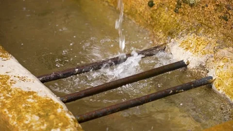 A splash of pure spring flowing water into a stone channel with a metal grate Vídeos de archivo 200098731