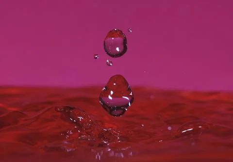 Splash resulting from the impact of a drop with a container full of water Stock Photos