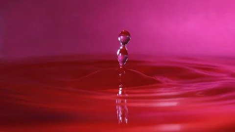 Splash resulting from the impact of a drop with a container full of water Stock Photos