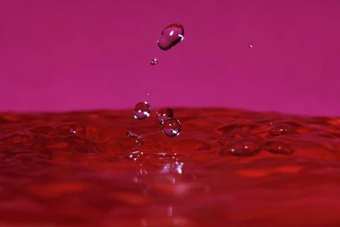 Splash resulting from the impact of a drop with a container full of water Stock Photos
