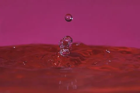 Splash resulting from the impact of a drop with a container full of water Stock Photos