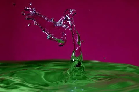 Splash resulting from the impact of a drop with a container full of water Stock Photos