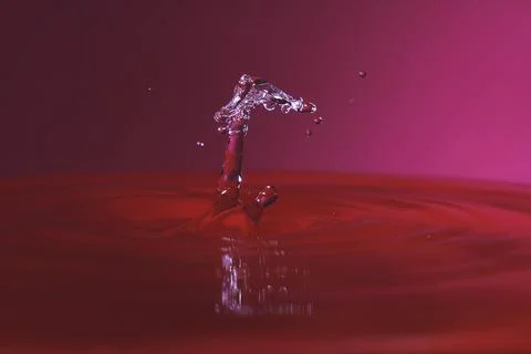 Splash resulting from the impact of a drop with a container full of water Stock Photos