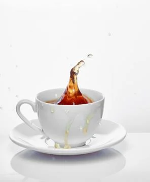 Splash of tea in the cup isolated on white Foto stock