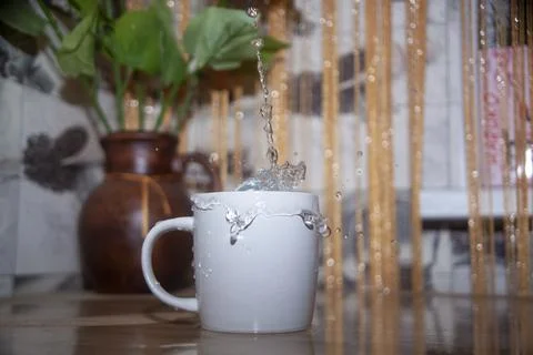 Splash of water in a mug on the table Stock Photos