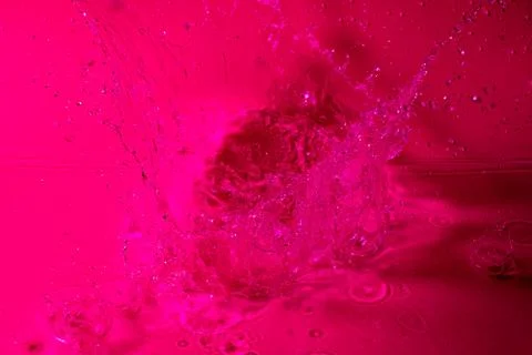 Splash of water on a red background. Abstract wallpaper Stock Photos
