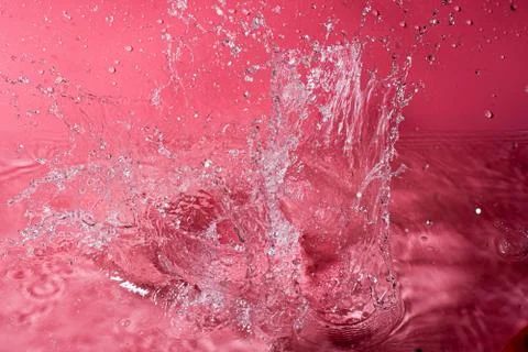 Splash of water on a red background. Abstract wallpaper Stock Photos