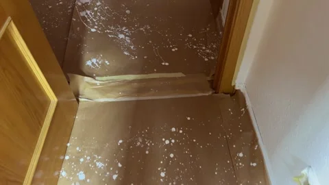 Splashed white paint on protective paper covering a wooden floor Видео 341362980