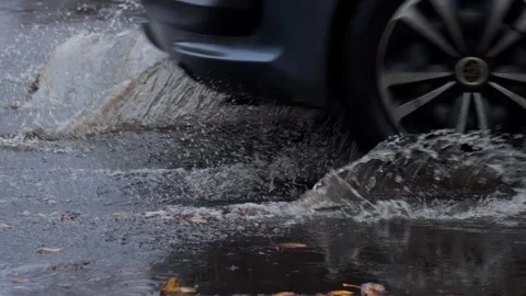 Splashes from car wheels on the road while driving through puddles in the city Stockbeeldmateriaal 310937635