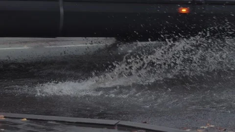 Splashes from car wheels on the road while driving through puddles in the city Stock Footage 310937727
