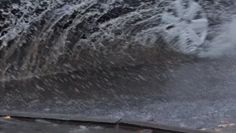 Splashes from car wheels on the road while driving through puddles in the city Stock Footage 312594886