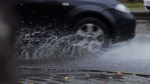 Splashes from car wheels on the road while driving through puddles in the city Video stock 313890652