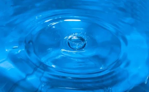Splashes from a drop of water. Rain drops on a blue background. The texture o 스톡 사진