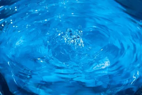 Splashes from a drop of water. Rain drops on a blue background. The texture o Stock Photos
