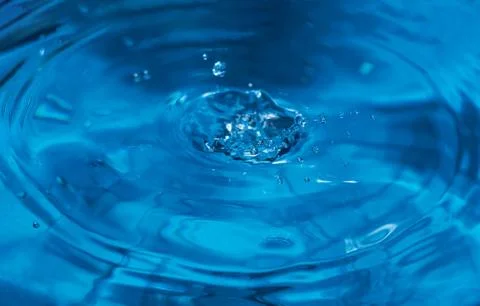 Splashes from a drop of water. Rain drops on a blue background. The texture o Stock Photos