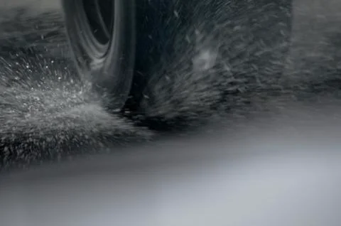 Splashes flying from under the wheels of a freight vehicle speeding. Stock Photos