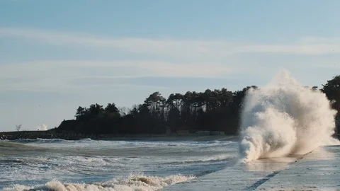 Splashes large strong waves crashing against the pier bright blue sky Stock Footage 129437196