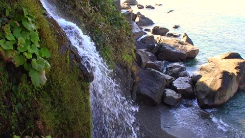 Splashes of a mountain waterfall against the background of a sea waves, stones Stock Footage 290165790