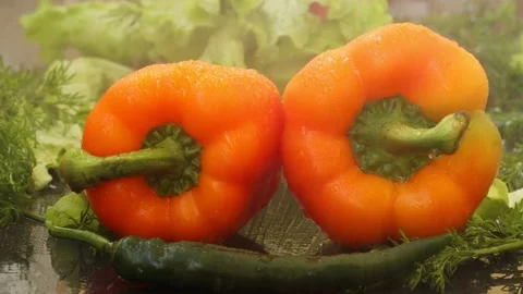 Splashes of water fall on two large juicy orange peppers Stock Footage 236542523