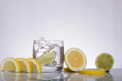 Splashes of water, lemon lime falling into a glass, isolated, reflection, whi Foto stock