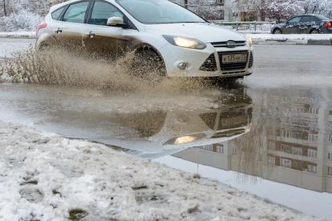 The splashes water from under the wheels of a vehicle moving through spring d Stock Photos