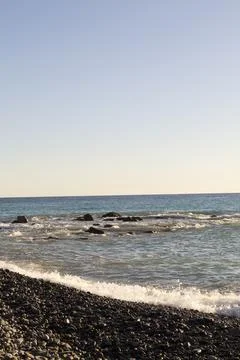 Splashes from the waves bumping against the rocky shore. Vertical photo Stock Photos
