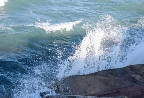 Splashes of waves on the concrete beachfront promenade. Stone steps to the se Foto stock