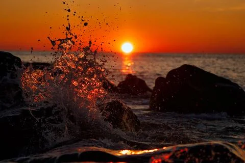 Splashes from waves during sunset on the sea Stock Photos