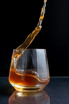 Splashes of whiskey on a black background Stock Photos