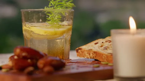 Splashing drops of lemon beverage and freshly baked bread by the candle 스톡 동영상 214072338