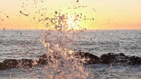 Splashing ocean spray in slow motion in front of setting sun. Video stock 115756484