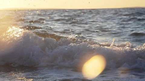 Splashing ocean wave with white foam under golden sunset light Stock Footage 337418782